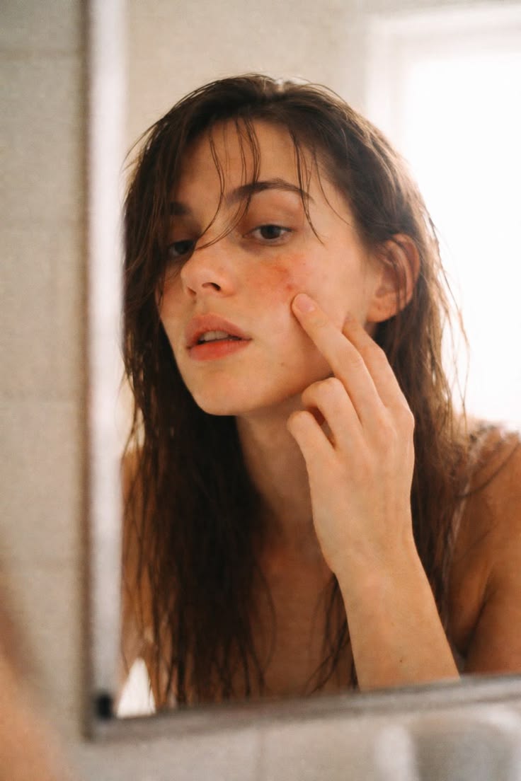Femme observant son acné dans un miroir